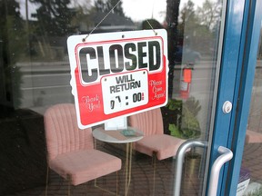 A closed sign is taped to the door of a storefront in the Calgary neighbourhood of   Kensington.