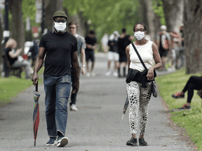 People wear face masks as they walk through a city park in Montreal.