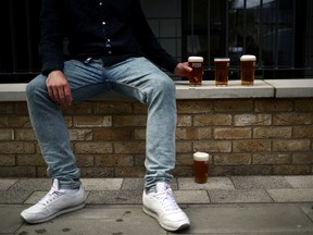 A customer sits next to freshly poured pints of beer from the Forest Road Brewing Co. pub on wheels vehicle during its delivery round in London on May 12, 2020.