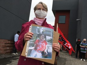 Pamela Bloomer holds a picture of her sister Merilee Locken, a resident of Scenic Bow Place care centre, outside the office of Community and Social Services Minister Rajan Sawhney.
