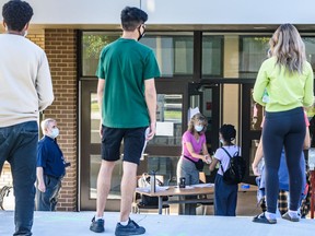 Students wait in line outside St. Francis High School for their diploma exam on Tuesday, August 4, 2020.