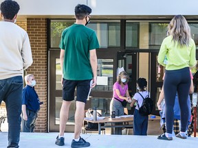 Students wait in line outside St. Francis High School for their diploma exam on Tuesday, August 4, 2020.