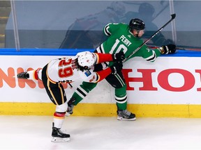 EDMONTON, ALBERTA - AUGUST 11: Dillon Dube #29 of the Calgary Flames checks Corey Perry #10 of the Dallas Stars into the boards during the third period in Game One of the Western Conference First Round during the 2020 NHL Stanley Cup Playoffs at Rogers Place on August 11, 2020 in Edmonton, Alberta, Canada.
