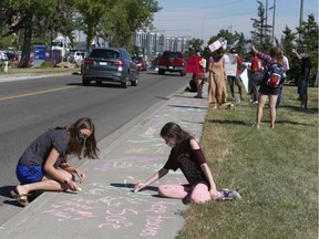 Protesters draw chalk messages on the sidewalk in front of Health Minister Tyler Shandro's constituency office in southwest Calgary on Friday, Aug. 21, 2020.