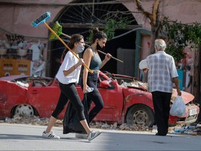 Lebanese volunteers walk with brooms in the devastated Gemmayzeh neighbourhood in Beirut, on August 11, 2020, following a huge chemical explosion that devastated large parts of the capital.