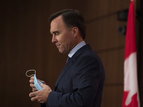 Minister of Finance Bill Morneau removes his mask as he prepares to announce his resignation during a news conference on Parliament Hill in Ottawa, on Monday, Aug. 17, 2020.