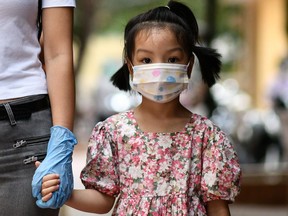 A young girl holds her mother's hand while waiting to be tested at a makeshift rapid testing centre in Hanoi on August 1, 2020, as Vietnam records a rise in cases of the COVID-19 coronavirus. - Vietnam recorded its first coronavirus death on July 31, state media reported, as the pandemic rebounds in a country previously been praised for stubbing out the contagion.