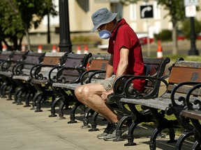 A man wearing a face mask rests on a bench in downtown Edmonton on Wednesday, Aug. 19, 2020. The city has seen an uptick in COVID-19 cases.