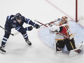 CP-Web.  Calgary Flames goalie Cam Talbot (39) makes the save as Winnipeg Jets' Nikolaj Ehlers (27) tries to knock the puck loose during second period NHL qualifying round game action in Edmonton, on Tuesday August 4, 2020.