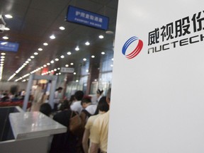 Airline passengers stand near a Nuctech Co. THSCAN RM 1000 Radioactivity Monitor at the airport in Dandong, Liaoning province, China, on Thursday, Aug. 13, 2009.