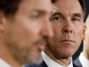 Former finance minister Bill Morneau looks at Prime Minister Justin Trudeau during a press conference in Ottawa on March 11, 2020.