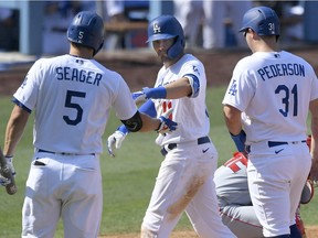 LOS ANGELES, CA - SEPTEMBER 27: Corey Seager #5 of the Los Angeles Dodgers and Joc Pederson #31 congratulate A.J. Pollock #11 on his home run in the seventh inning against the Los Angeles Angels at Dodger Stadium on September 27, 2020 in Los Angeles, California.