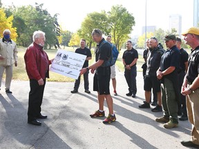 Field of Crosses founder Murray McCann (L) accepts a cheque from Calgary Police Sgt Travis Juska (R), representing the CPS Honour Guard, in Calgary on Sunday, September 20, 2020. The Honour Guard walked 11 km through downtown Calgary to the Field of Crosses on Memorial Drive. The walk symbolizes the journey the fallen members will have taken from enlistment (at Mewata), to internment (at the Union Cemetery) to a place of eternal memory (at the Field of Crosses).