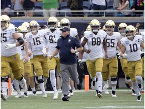 CP-Web.  FILE - In this Dec. 28, 2019, file photo, Notre Dame head coach Brian Kelly, center, runs onto the field with his players before the Camping World Bowl NCAA college football game against Iowa State in Orlando, Fla. The Atlantic Coast Conference and Notre Dame are considering whether the Fighting Irish will give up their treasured football independence for the 2020 season play as a member of the league.