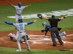 Aug 21, 2020; St. Petersburg, Florida, USA;  Toronto Blue Jays left fielder Lourdes Gurriel Jr. (13) is called safe at home by officials and teammates during the second inning of a game at Tropicana Field.  The call was later overturned. Mandatory Credit: Mary Holt-USA TODAY Sports ORG XMIT: USATSI-428686