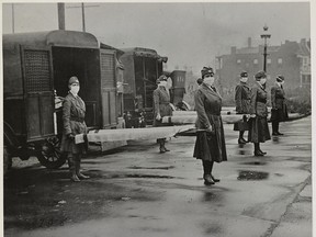 St. Louis Red Cross Motor Corps personnel hold stretchers next to ambulances in preparation of receiving victims of the influenza epidemic in October 1918.