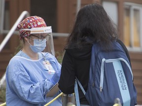A health-care worker takes a woman's details at a COVID-19 testing clinic in Montreal, Sunday, September 27, 2020, as the COVID-19 pandemic continues in Canada and around the world.