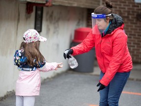 FILE PHOTO: A student has her hands sanitized in the schoolyard, as schools outside the greater Montreal region begin to reopen their doors amid the coronavirus disease (COVID-19) outbreak, in Saint-Jean-sur-Richelieu, Quebec, Canada May 11, 2020.