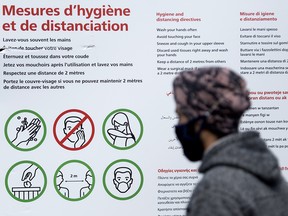 A man wears a face mask as he looks at a COVID-19 information sign in Montreal on Sept. 20, 2020.