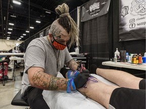 Tattoo artist Sam Patten inks a design on Joshua MacPherson's leg at the Calgary Tattoo and Arts Festival at BMO Centre on Friday, Oct. 16, 2020.