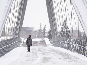 A Pedestrian crosses the George C. King Bridge on Bow River on a snowy cold morning on Friday, October 23, 2020.