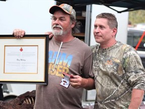 Ray Mckay (L) with fellow veterans' helper Michael Rehaeuser displays Minister of Veterans Affairs Commendation at a barbecue last month.