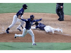 Randy Arozarena of the Tampa Bay Rays slides into home plate during the ninth inning to give his team an 8-7 victory, as Kevin Kiermaier celebrates, against the Los Angeles Dodgers in Game 4 of the World Series at Globe Life Field in Arlington, Texas, on Oct. 24, 2020.