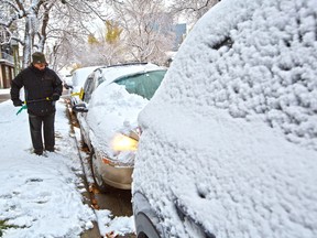 Ezy Tabrizi clears the overnight snow from his car in Crescent Heights on Wednesday, October 14, 2020. More snow flurries are forecast over the next few days.