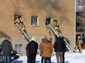 Residents look on as Calgary firefighters deal with a fire in a six-unit apartment building in the 100 block of 27th Avenue N.W. on Sunday, October 25, 2020.