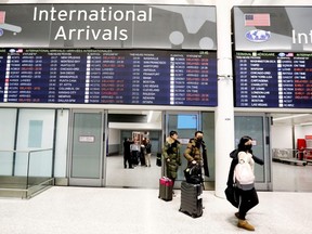 FILE - Travellers wear masks at Pearson airport arrivals, shortly after Toronto Public Health received notification of Canada's first presumptive confirmed case of coronavirus, in Toronto, Ontario, Canada January 25, 2020.