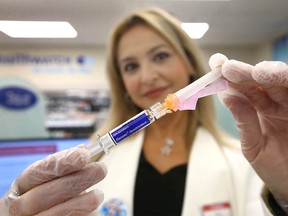 Amani Chehade, prescribing pharmacist at Aspen Landing Shoppers Drug Mart in Calgary, holds a vile of flu vaccine on Sunday, October 18, 2020.