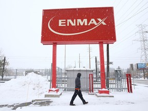 A pedestrian walks under a sign at Enmax Corporation Head Office in Calgary on Friday, October 23, 2020.