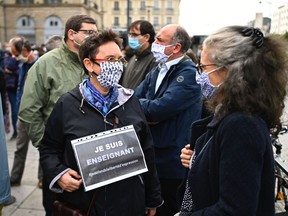 A woman, holding a sign reading "I am a teacher", speaks with another person during a demonstration in Rennes, western France, on October 17, 2020, one day after a teacher was beheaded by an attacker who was shot dead by policemen in Conflans-Sainte-Honorine, 30kms northwest of Paris. - The man suspected of beheading on October 16, 2020, a French teacher who had shown his students cartoons of the prophet Mohammed was an 18-year-old born in Moscow and originating from Russia's southern region of Chechnya, a judicial source said on October 17. Five more people have been detained over the murder on October 16 ,2020 outside Paris, including the parents of a child at the school where the teacher was working, bringing to nine the total number currently under arrest, said the source, who asked not to be named. The attack happened at around 5 pm (1500 GMT) near a school in Conflans Saint-Honorine, a western suburb of the French capital. The man who was decapitated was a history teacher who had recently shown caricatures of the Prophet Mohammed in class.