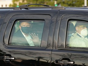 US President Trump waves from the back of a car in a motorcade outside of Walter Reed Medical Center in Bethesda, Maryland on October 4, 2020.