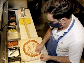 Mike Garth, co-owner of Pizzaface, is seen dressing a pizza in Community Natural Foods where they have opened a walk-in style pizza restaurant named Pizza face. Thursday, October 1, 2020. Brendan Miller/Postmedia