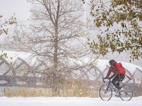 A cyclist rides along Memorial Drive N.W. with Peace Bridge in the background on a snowy Friday morning in Calgary, Oct. 23, 2020.