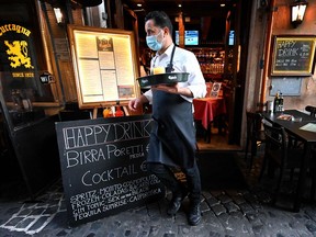 A waiter wearing a face mask brings a drink to a table in a bar Oct. 19, 2020, in central Rome.