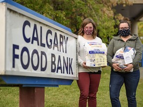 Morissa Villeneuve, community engagement supervisor with Calgary Food Bank, and Caitlin Reid, community engagement coordinator, pose for a photo with white bags filled with donations on Friday, Sept. 18, 2020.