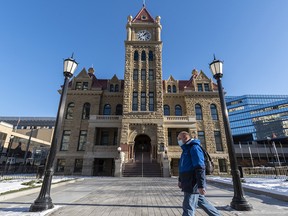 A masked pedestrian walks in front of the Old City Hall in downtown Calgary on Monday, Nov. 23, 2020.
