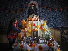 Liz Vigueras finishes the altar at the Highwood Museum in High River, Alta., for Day of the Dead celebrations. This year the altar is also remembering those who have died from COVID-19.