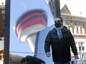 Martin Bouchard walks by a reflective mural of the Calgary Tower as COVID cases continue to increase in Calgary on Saturday, November 21, 2020.
