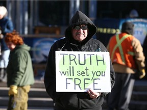 A supporter carries a sign during a large rally in Municipal Plaza in downtown Calgary on Saturday, November 28, 2020. About 1000 participants, from a few different groups were opposed to a number of things-the federal, provincial and civic governments, anti-masking, and end the lockdown. The group eventually marched up and down Stephen Ave Mall. Jim Wells/Postmedia