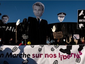 Demonstrators hold effigies of French President Emmanuel Macron, French Interior Minister Gerald Darmanin and Paris police prefect Didier Lallement on the Place de la Republique in Paris on November 28, 2020 during a protest against the "global security" draft law, which Article 24 would criminalise the publication of images of on-duty police officers with the intent of harming their "physical or psychological integrity". - Dozens of rallies are planned on November 28 against a new French law that would restrict sharing images of police, only days after the country was shaken by footage showing officers beating and racially abusing a black man.
