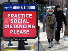 A sign outside Mission Wine & Liquor reminds Calgarians to stay apart as COVID-19 cases surge in the city on Monday, November 16, 2020.