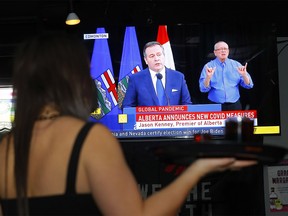 Waitress Kata Supernault from Side Street Pub and Grill watches as Alberta Premier Jason Kenney places new restrictions to help fight the rise of COVID-19 in Calgary on Tuesday, Nov. 24, 2020.