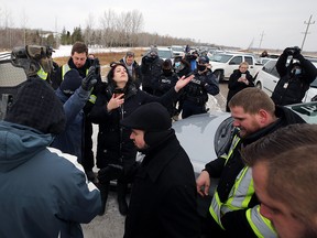 Church of God supporters pray as RCMP prepare to tow a vehicle blocking the highway outside the church south of Steinbach, Man., on Sun., Nov. 29, 2020. RCMP blocked the entrance, preventing a planned drive-by service.