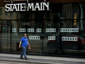 A pedestrian, wearing a mask to protect against COVID-19, walks past a message of support for nurses at the State & Main restaurant, 10065 Jasper Ave., in Edmonton, May 20, 2020.
