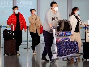 People wearing protective face masks carry their luggage at Capital Airport, following an outbreak of the coronavirus disease (COVID-19), in Beijing, China, November 5, 2020.