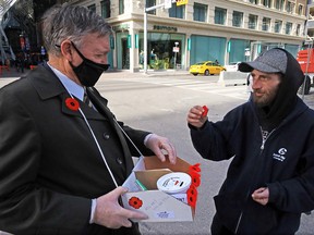 Robert Misenei buys a Remembrance Day poppy from Royal Canadian Legion volunteer Ray Leitch on Stephen Avenue in Calgary on Tuesday, Nov. 3, 2020.