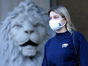 Brooke Stoilen walks past a lion statue at Calgary city hall on Wednesday, Nov. 25, 2020.